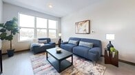 This contemporary 570 square foot apartment in Milwaukee offers a harmonious blend of style and functionality. The open-concept floor plan maximizes space, seamlessly integrating the living room and kitchen. The living area is adorned with large windows that flood the space with natural light, complemented by sleek blue furnishings and a modern coffee table.

The kitchen is a chef's delight, boasting taupe cabinetry, stainless steel appliances, and a generous island with seating for four. Pendant lighting adds a touch of elegance, while the light-colored countertops enhance the bright, airy feel.

The bedroom, measuring 120 square feet, features a comfortable bed with crisp linens and decorative pillows. Wood-look flooring extends throughout, creating a cohesive aesthetic. The bathroom showcases a modern vanity with ample storage and artistic wall decor.

Thoughtful touches like potted plants, contemporary artwork, and a circular mirror in the entryway add personality to the space. The apartment's neutral color palette is punctuated by pops of blue, creating a calming yet stylish atmosphere. This well-designed home offers the perfect balance of comfort and urban sophistication.