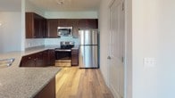 This single-story unit in Lebanon, Tennessee offers a thoughtfully designed layout with a consistent blend of materials and finishes throughout. The kitchen serves as a functional centerpiece, featuring rich dark-espresso cabinetry, granite-look countertops, and a full suite of stainless steel appliances, including a refrigerator, range, and over-the-range microwave. Wood-look plank flooring flows through the kitchen and into the adjacent dining and living areas, where a ceiling fan with light fixture provides overhead illumination. A window along one wall brings in natural light, and a partial countertop partition visually connects the kitchen to the dining space.

The bedrooms are finished with plush carpeting and equipped with ceiling fans. Each room receives natural light through blinded windows, with outdoor views visible from select rooms. The primary bedroom benefits from a spacious walk-in closet outfitted with wire shelving for organization. The primary bathroom features a dual-sink vanity with granite-look countertops, dark cabinetry, large mirrors, and hardwood-style flooring. A secondary full bathroom includes a tub-shower combination, toilet, and matching wood-look floors, maintaining a cohesive aesthetic throughout the unit.