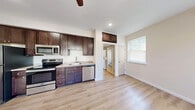 Located at 119 Village Circle in Ithaca, NY, this single-floor unit offers a clean, modern interior defined by light hardwood-style flooring and neutral wall tones that carry consistently throughout the space. The open kitchen is a functional centerpiece, outfitted with rich dark-brown shaker cabinetry extending to the ceiling for ample storage, light granite-style countertops, and a full suite of stainless steel appliances including a refrigerator, electric range, built-in microwave, and dishwasher. Recessed lighting and a ceiling fan enhance the kitchen and adjoining living area, which benefits from multiple windows that invite natural light and provide a bright, airy atmosphere. The living space is equipped with a wall-mounted ductless mini-split system for efficient heating and cooling year-round. The bedroom is generously proportioned, featuring two windows that further promote natural light and ventilation. The bathroom is finished with dark-wood cabinetry paired with a light countertop and includes a stacked washer and dryer unit, integrating laundry conveniently within the same space. Clean lines, consistent finishes, and thoughtful functionality characterize the overall design of this well-appointed unit.