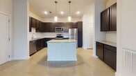 Located at 1040 Flathead Dr in Dripping Springs, Texas, this single-story home offers a clean, modern aesthetic defined by polished concrete floors that flow seamlessly throughout the entire residence. The open-concept layout creates a generous, connected living space anchored by a spacious living room equipped with a ceiling fan and access to the outdoors via a sliding glass door, filling the space with natural light.

The kitchen is a standout feature, showcasing dark espresso cabinetry that contrasts beautifully with light granite countertops and a classic white subway tile backsplash. A central island with pendant lighting above provides additional prep and gathering space. Stainless steel appliances — including a refrigerator, electric range, over-the-range microwave, and dishwasher — complete the well-appointed culinary area.

The bedrooms are bright and airy, each featuring windows with blinds that allow for natural light and privacy. Neutral walls and polished concrete floors maintain the cohesive, contemporary feel found throughout the home.

The bathroom is thoughtfully designed with dark cabinetry, dual sinks set into granite countertops, a large mirror, and a tiled tub and shower surround, delivering both function and style. Overall, this home presents a modern, low-maintenance living environment in the heart of Dripping Springs.