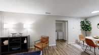 This thoughtfully laid-out one-bedroom, one-bathroom unit offers a functional and comfortable living experience across a single floor. The open-concept living, dining, and kitchen area forms the heart of the space, creating a seamless flow for everyday living and entertaining. The living room is bright and welcoming, featuring wood-style flooring, a textured ceiling, and windows with blinds that allow natural light to filter in. A peninsula counter separates the kitchen from the dining area, providing a casual breakfast bar-style division. The kitchen is well-equipped with white shaker cabinetry, white countertops, a stainless steel refrigerator, an electric range, a dishwasher, and ample upper and lower cabinet storage. A dedicated pantry adds extra storage convenience. A standout feature of this unit is the in-unit washer and dryer, tucked neatly within a closet area off the main living space. The bedroom offers a comfortable, proportionate layout with two windows that bring in natural light, and the room benefits from three closets providing generous storage. The bathroom is clean and functional, featuring a combined tub and shower, a vanity with under-sink storage, and wood-style flooring. The consistent neutral color palette and warm flooring throughout give the space a cohesive, modern feel.