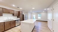 Located at 27th Ave in Council Bluffs, Iowa, this single-floor, 3-bedroom, 2-bathroom residence offers a well-organized and modern layout. Light hardwood flooring runs consistently throughout the home, creating a cohesive and bright aesthetic. The kitchen serves as a focal point, featuring rich dark wood cabinetry, a large central island with a marble-style countertop, stainless steel appliances including a refrigerator, range, microwave, and dishwasher, and recessed lighting overhead. The kitchen flows seamlessly into an open living area with natural light streaming in through multiple windows. The primary bedroom offers a comfortable footprint with natural light from paired windows and a set of double doors leading to a closet. The additional bedrooms are clean and well-proportioned, each with light-toned walls, hardwood floors, and windows providing natural light. Both bathrooms are finished in a bright, minimal style — one features a full tub-shower combination with white tile surround, while the other includes a wood-toned vanity with a lighted mirror above. Dark baseboards throughout provide a subtle contrast to the light flooring and neutral walls, lending the home a polished, contemporary character.