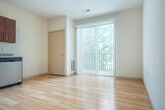 Located at 1300 Post Rd in Fitchburg, WI, this well-appointed one-bedroom, one-bathroom unit offers a thoughtfully designed single-floor layout that maximizes every square foot of its compact footprint. Light hardwood flooring runs throughout the main living areas, lending warmth and continuity to the space.

The combined kitchen and living room serves as the heart of the unit, featuring rich cherry wood cabinetry, stainless steel appliances including a refrigerator, range, microwave, and dishwasher, and neutral countertops. A sliding glass door floods the area with natural light and opens directly onto a private patio, which overlooks a lush, tree-lined outdoor setting.

A hallway connects the main living area to the remaining rooms, with a wall-mounted thermostat conveniently positioned along the route. The bathroom is finished with warm wood-toned cabinetry, a dual-sink vanity with chrome fixtures, a large mirror with overhead lighting, and durable tile-style flooring. The bedroom is carpeted for comfort and offers a quiet, private retreat. A dedicated laundry area houses a stacked washer and dryer unit, adding everyday convenience. A closet provides additional storage. The overall aesthetic is clean, modern, and functional.