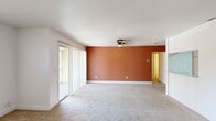 This single-story residence offers a thoughtfully organized layout across two bedrooms and two bathrooms. The living area serves as the heart of the home, distinguished by a warm terracotta accent wall, neutral carpet flooring, and a ceiling fan overhead. Sliding glass doors along one wall invite natural light and provide outdoor access. The space flows into a hallway connecting the remaining rooms.

The kitchen features light grey laminate flooring, white cabinetry with brushed nickel hardware, speckled countertops, and black appliances including a full-size refrigerator and dishwasher, offering a clean, functional workspace.

Both bedrooms are finished with light-toned luxury vinyl plank flooring and neutral walls, each receiving natural light through windows fitted with blinds. The generously sized primary bedroom includes a sliding-door closet with built-in shelving and hanging rods for ample storage.

The bathrooms maintain a clean, minimal aesthetic with speckled countertop vanities, large mirrors, and matte black hardware accents. One bathroom features a full tub-shower combination with tiled surround. Throughout, the space presents a cohesive, move-in ready environment with updated finishes and a light, neutral palette.