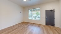 Located at 2250 Gable Rd in Saint Helens, Oregon, this two-story apartment offers three bedrooms, two bathrooms, and a thoughtfully arranged layout across two floors. The main level features an open-concept kitchen and living area with light hardwood-style flooring throughout. The kitchen is outfitted with two-tone cabinetry — white upper cabinets paired with charcoal lower drawers — along with a full suite of white appliances including a refrigerator, dishwasher, electric range, and overhead ventilation hood. A staircase with recessed lighting connects the main level to the upper floor. The living area benefits from a large window that brings in natural light and exterior views. Both bathrooms follow a consistent, clean design with full soaking tubs, white surround walls, a toilet, and a dark-cabineted vanity with a single sink. The bedrooms feature neutral carpet flooring and crisp white walls, with the primary bedroom offering generous proportions and a wide sliding double closet. Additional bedrooms include windows with horizontal blinds, allowing natural light. The hallway and entrance complete the layout, providing smooth flow throughout the home.