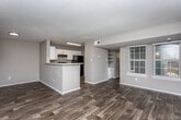 Located at 1955 Bells Ferry Rd in Marietta, Georgia, this single-floor residence offers a well-organized layout designed for comfortable everyday living. The open-concept living and dining area is finished with rich, dark hardwood-style flooring that extends throughout the main living spaces, creating a cohesive and contemporary aesthetic. Natural light filters in through multiple windows dressed with classic white blinds, brightening the neutral gray-toned walls throughout.

The kitchen is a functional highlight of the space, featuring crisp white cabinetry with brushed nickel hardware, granite-style countertops, a breakfast bar peninsula, and black appliances including a refrigerator, electric range with overhead ventilation, and dishwasher. The peninsula provides additional prep space and casual seating while connecting the kitchen to the main living area.

Multiple bedrooms are carpeted in a neutral tone, offering a comfortable retreat. The primary bedroom stands out with a bay-style window configuration that allows ample natural light and includes a walk-in closet and direct access to an en-suite bathroom. Additional bedrooms also feature closet storage.

Both bathrooms are consistently appointed with white vanity cabinetry, granite-style countertops, single-basin sinks, and tub-shower combinations. A hallway with built-in shelving connects the private areas of the home, rounding out a practical and well-designed floor plan.
