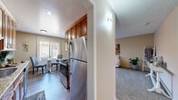 This single-story residence in Pleasanton, California offers a thoughtfully designed layout with a neutral warm palette and an abundance of natural light throughout. The kitchen is well-equipped, featuring rich medium-tone wood cabinetry, granite countertops, stainless steel appliances including a refrigerator and range, and wood-style flooring. A compact dining area adjacent to the kitchen provides a bright spot for meals, with a window overlooking the exterior.

The living room is generously sized, finished with plush carpeting and a large sliding glass door that fills the space with natural light while providing outdoor access. A secondary sitting or flex area connects seamlessly to the main living space, adding versatility to the floor plan.

Both bedrooms are carpeted and well-lit, each featuring large windows with vertical blinds. The primary bedroom offers ample room for a full furniture arrangement. The two bathrooms are finished with granite-topped wood vanities and wood-style flooring; one includes a tub-shower combination, while the other features a sleek walk-in shower with sliding glass doors. Together, these spaces create a cohesive and comfortable living environment.