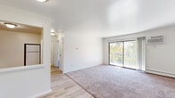 Located at 1240 W 52nd Pl in Merrillville, Indiana, this single-floor unit offers a clean, functional layout with a bright and open feel throughout. The living area is generously sized, featuring a combination of light wood-style flooring and plush carpeting, with a large sliding glass door that opens to a railed balcony overlooking lush, tree-lined surroundings, filling the space with natural light.

Adjacent to the living area, the kitchen is equipped with warm wood-toned cabinetry, dark countertops, a double-basin sink, and a white electric range, providing practical functionality for everyday cooking.

The bedrooms are carpeted and finished with crisp white walls, offering a calm and neutral environment. Each room includes baseboard heating and wall-mounted air conditioning units for year-round climate control. One bedroom features a sliding window with views of the surrounding greenery and yard.

The bathroom is finished in a clean, all-white palette with light wood-style flooring, a single-sink vanity with mirrored cabinet, a full bathtub with tiled surround, and bright overhead lighting. Hallway closets provide additional storage throughout the unit. Overall, the space presents a straightforward, well-maintained layout suited for comfortable everyday living.