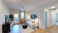This well-appointed single-floor residence in Moreno Valley, California offers a thoughtfully designed layout with a clean, contemporary aesthetic throughout. The living room serves as an inviting centerpiece, featuring light wood-style flooring, a ceiling fan, and a glass door that opens to a private outdoor balcony, filling the space with natural light. Adjacent to the living area is a cozy dining nook with wood flooring and modern wall art, providing an intimate setting for meals. The kitchen is a standout feature, outfitted with crisp white shaker cabinetry, dark quartz countertops, a grey subway tile backsplash, stainless steel appliances including a gas range and French door refrigerator, and a breakfast bar peninsula ideal for casual dining. The bedrooms offer comfortable retreats, each with plush carpeting and generous closet space, including a room with mirrored sliding closet doors. The bathrooms are finished with white shaker vanities, dark quartz countertops, and wood-style flooring. The full bathroom includes a tub-shower combination, while a secondary bathroom provides a single-vanity layout. Neutral tones and consistent finishes throughout create a cohesive and modern living environment.