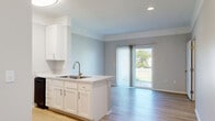 Located at 124 Lippazon Way in Delaware, Ohio, this efficiently designed one-bedroom, one-bathroom home offers a well-organized single-floor layout. The open-concept living area seamlessly integrates the kitchen, dining, and living spaces, creating a bright and cohesive environment. The kitchen is outfitted with crisp white cabinetry, light quartz-style countertops, a stainless steel double-basin sink, and black appliances including a range and refrigerator. Light hardwood-style flooring runs throughout the main living areas, complementing the soft, neutral wall tones. A sliding glass door floods the living area with natural light and provides direct access to a private patio with outdoor views. The bedroom features plush carpeting, vaulted ceilings, and two large windows that invite abundant natural light. Three closets offer generous storage throughout the home. The bathroom includes a full tub/shower combination, a vanity with a stone-top surface, and brushed gold hardware accents. A dedicated laundry room houses full-size washer and dryer units, adding everyday convenience. A utility room rounds out the thoughtfully arranged floor plan, making this home both functional and comfortable.