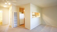 This single-floor space offers a practical and well-organized layout, as revealed by the 3D floor plan overview. The entry area transitions from hardwood-style flooring near the front door to soft wall-to-wall carpeting that extends throughout the main living and sleeping areas. Neutral beige walls and textured ceilings maintain a consistent, understated aesthetic throughout the unit.

The kitchen is efficiently designed with warm honey-toned wood cabinetry, light speckled countertops, and white appliances including a gas range and an over-the-range microwave. A sink is positioned nearby, making the space highly functional for everyday cooking.

The living area is generously proportioned and bright, with a sliding glass door fitted with sheer white curtains opening to a private balcony that overlooks greenery, allowing natural light to pour in. An additional carpeted room, suitable for use as a bedroom, features a window with an outdoor view and ample wall space.

The bathroom is clean and straightforward, featuring a full tub-shower combination with chrome fixtures, a small window above for natural ventilation, and hardwood-style flooring. The space is finished with white surfaces and a vanity with a sink.

Overall, the space presents a neutral, move-in-ready environment with consistent finishes and practical amenities throughout.