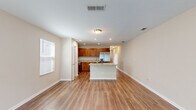 Located at 9872 Trout Tides Blvd in Jacksonville, FL, this two-story home offers a well-organized layout spread across two floors. The main level hosts the kitchen, living room, and garage, while the upper floor accommodates the bedrooms and additional bathrooms. Wood-look flooring flows consistently throughout the home, lending a warm, cohesive aesthetic.

The open-concept kitchen and living area form the heart of the main floor. The kitchen is outfitted with rich, warm-toned cabinetry, granite countertops, a stainless steel refrigerator with an in-door dispenser, recessed lighting, and a central island that doubles as a prep and dining space. Natural light filters in through nearby windows, brightening the entire area.

Each of the three bathrooms features granite-topped vanities with wood-toned cabinetry, and at least one includes a full tub-shower combination. The hallway on the upper level is bright and well-lit, connecting the three bedrooms with clean lines and a neutral palette. The spacious primary bedroom offers generous square footage. Additional bedrooms provide natural light through windows with blinds. The attached garage features a standard roll-up door with a window panel above, offering additional storage or parking utility.