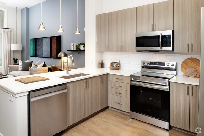 Modern kitchen with oak cabinetry, white tile backsplash, white quartz countertops, stainless steel appliances, and pendant lighting - Avalon Durham