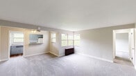 Located at 1002 Vermont Ave in Castle Shannon, PA, this one-bedroom, one-bathroom unit offers a comfortable and functional single-floor layout. The expansive living room is a standout feature, with plush wall-to-wall carpeting, neutral-toned walls, and a large corner window arrangement that floods the space with natural light and provides pleasant views of the surrounding greenery. A classic cast-iron radiator provides efficient heating, and a ceiling fan enhances air circulation. The living area flows seamlessly into the kitchen, which is accessible via a pass-through counter and features cabinetry, standard appliances, and wood-style flooring. Two interior doors from the living room provide access to the hallway and additional rooms, contributing to a well-organized layout. The bedroom is a comfortable, well-proportioned room with soft carpeting, neutral walls, and a window with a radiator beneath it, offering both natural light and warmth. The bathroom is clean and bright, finished with light tile flooring, a white vanity, and a tub-shower combination with a window for ventilation. A connecting hallway ties the rooms together efficiently. Overall, the unit presents a straightforward, practical living space with classic details throughout.