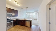 Located at 200 Hudson Ct in Wheeling, Illinois, this two-bedroom, two-bathroom residence offers a thoughtfully designed single-floor layout. The kitchen is a standout feature, showcasing rich dark wood cabinetry that extends to the ceiling, granite countertops, stainless steel appliances including a gas range, microwave, refrigerator, and dishwasher, and elegant pendant lighting over a functional peninsula with an undermount sink. Warm hardwood flooring grounds the kitchen's sophisticated aesthetic.

The living area is finished with plush carpeting and crisp white walls, creating a bright and welcoming atmosphere. A hallway connects the main living spaces to the bedrooms and bathrooms. The primary bedroom is a generous, well-proportioned retreat with soft carpeting and a large window that invites natural light and outdoor views. The second bedroom is equally comfortable, also featuring carpet and clean, neutral finishes.

Both bathrooms are finished with light tile flooring and include dark wood vanities with storage. The full bathroom features a tub-shower combination. A dedicated closet provides additional storage. The overall design balances practical functionality with modern finishes, making this a well-rounded residence in Wheeling, IL.
