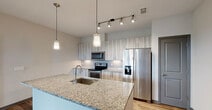 Located in Sarasota, FL, this thoughtfully designed 2-bedroom, 2-bathroom residence offers a comfortable and modern living experience across a single floor. The open-concept layout seamlessly connects the kitchen, dining, and living areas, creating a bright and functional shared space. The kitchen is a standout feature, boasting granite countertop island with a built-in sink, stainless steel appliances including a refrigerator with ice maker, electric range, and microwave, complemented by contemporary marbled cabinetry and stylish pendant lighting with track lighting overhead. Wood-look flooring flows throughout the main living areas, adding warmth and continuity. The generously sized primary bedroom features plush carpeting, a ceiling fan, and multiple windows that invite natural light and offer views of the surrounding greenery. The second bedroom is similarly carpeted with its own ceiling fan and window. The space includes four closets, highlighted by a walk-in closet with wire shelving for ample storage. Both bathrooms are clean and modern, with one featuring a tiled tub-shower combination and granite vanity. Additional conveniences include an in-unit laundry area and a private patio, rounding out this well-equipped Sarasota residence.