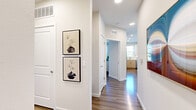 This thoughtfully designed single-floor residence combines modern aesthetics with functional living. A clean, well-lit hallway serves as the central spine of the home, featuring recessed lighting, wood-look flooring, and curated wall art that sets an inviting tone from the moment you enter.

The open-concept kitchen is a standout feature, equipped with stainless steel appliances including a refrigerator, range, and built-in microwave. Two-tone cabinetry pairs light wood lower cabinets with crisp white upper cabinets, complemented by a white quartz countertop, tile backsplash, and a generous island ideal for meal prep or casual dining.

The living area offers generous proportions with neutral walls, wood-look flooring, and abundant natural light filtering through large windows. The bedrooms are well-appointed, each featuring wood-look flooring, large windows with exterior views, and ample space. The primary bedroom includes a spacious walk-in closet with wire shelving for organized storage.

The bathroom is finished with a light wood vanity, white countertop, large mirror, and a shower-tub combination. Recessed lighting and wood-look flooring carry the home's cohesive design language throughout, creating a clean, contemporary ambiance across every room.