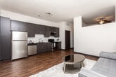 Located at 1701 Broad St in Chattanooga, Tennessee, this single-floor residence offers a thoughtfully designed layout with contemporary finishes throughout. Rich hardwood-style flooring flows seamlessly from room to room, complemented by crisp white walls and dark trim that create a striking modern contrast.

The kitchen is a standout feature, outfitted with sleek dark cabinetry, dark granite countertops, a classic white subway tile backsplash, and a full suite of stainless steel appliances including a refrigerator, range, microwave, and dishwasher. The space is well-lit and opens to the main living area, promoting an easy, functional flow.

The living area offers a calm, open atmosphere with neutral tones and ample room for comfortable furnishings. A wide hallway connects the spaces, accented by a sliding barn-style door that adds a modern-industrial touch.

The bedroom is generously sized and includes convenient in-unit washer and dryer access, a practical amenity that adds significant day-to-day value. The bathroom features a full tub-shower combination with white tile surround, dark vanity cabinetry with granite countertops, and hardwood-style flooring that ties the space together cohesively.

Throughout the unit, the design balances modern aesthetics with functional living, making this Chattanooga residence a well-rounded and attractive space.
