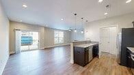 Located at 1125 Old Graves Mill Rd in Lynchburg, VA, this well-appointed one-bedroom, one-bathroom residence offers a thoughtfully designed single-floor layout with generous living space. The open-concept living, dining, and kitchen area forms the heart of the home, anchored by warm hardwood-style flooring that flows seamlessly throughout. The kitchen is a standout, featuring rich dark cabinetry, granite countertops, stainless steel appliances including a refrigerator, range, microwave, and dishwasher, and a central island with pendant lighting overhead — ideal for both cooking and casual dining. The living area is bright and airy, benefiting from large windows and a sliding glass door that opens to a private balcony, while a sleek linear fireplace adds a modern focal point. A ceiling fan complements the space for year-round comfort. The spacious primary bedroom is carpeted for warmth, outfitted with a ceiling fan, corner windows that invite natural light, and access to closet space. The full bathroom features tile flooring, a tub-shower combination, and a dark-cabineted vanity with a white countertop. Additional functional spaces include a laundry area and utility room, rounding out this clean, modern residence.