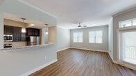 This single-story, two-bedroom, two-bathroom residence offers a thoughtfully designed layout with a blend of modern finishes and functional living spaces throughout. The open-concept living and dining area is anchored by warm wood-style hard-surface flooring, crown molding, and a ceiling fan, while multiple windows fitted with blinds allow ample natural light to fill the space. French doors with a transom window further brighten the living area and provide access to the outdoors.

The kitchen is positioned adjacent to the living area and features a pass-through granite-style countertop breakfast bar, dark espresso cabinetry, a white subway tile backsplash, and a full suite of stainless steel appliances including a refrigerator, range, and over-the-range microwave. Pendant lighting above the bar adds a refined touch.

Both bedrooms offer neutral tones and are carpeted for comfort. One bedroom includes hardwood-style flooring and a ceiling fan, along with a window for natural light. Each bedroom provides access to a closet for storage.

The two bathrooms are consistent in finish, each showcasing granite-style countertops, dark vanity cabinetry, undermount sinks, large mirrors, and wood-style flooring, presenting a clean and cohesive aesthetic throughout the home.