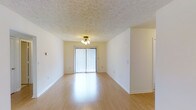 This 3-bedroom, 2-bathroom residence is thoughtfully laid out across a single floor, offering a comfortable and functional living environment. The main living area is bright and open, featuring smooth hardwood-style flooring that reflects natural light and adds warmth throughout the space. A textured ceiling with a central light fixture adds character, while large sliding glass doors dressed with vertical blinds lead to an outdoor area, filling the room with abundant natural light and providing a seamless connection to the exterior. The neutral, light-toned walls create a clean and versatile backdrop, making the space easy to personalize. The generous proportions of the living area offer ample room for a variety of furniture arrangements, making it suitable for both relaxing and entertaining. The unit includes three well-sized bedrooms ideal for families or those needing dedicated workspace. Two full bathrooms add convenience and practicality to the layout. Overall, this residence combines a straightforward, efficient floor plan with bright, airy interiors and a welcoming ambiance, making it a comfortable and livable home.