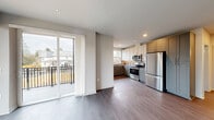 This well-appointed 2-bedroom, 2-bathroom residence features a thoughtfully designed open-concept layout with modern finishes throughout. The living area is bathed in natural light from large sliding glass doors that lead to a private balcony overlooking a green outdoor setting, creating a seamless indoor-outdoor connection. The kitchen is equipped with stainless steel appliances, including a refrigerator, electric range, and microwave, complemented by two-tone cabinetry in white and gray, a tile backsplash, and ample storage. Durable hardwood-style flooring flows throughout the main living areas, adding warmth and continuity. A central hallway with recessed lighting connects the bedrooms and bathrooms, providing a clean and efficient flow. The generously sized primary bedroom features plush carpeting and a large window overlooking the outdoors. The second bedroom is equally comfortable with carpet flooring, a double closet, and a natural light-filled window. Both bathrooms are finished with stylish gray cabinetry, dark granite countertops, patterned tile flooring, and dark-bronze fixtures. One bathroom includes a soaking tub with tiled surround, while the other offers a separate shower. This residence combines contemporary design with practical functionality.