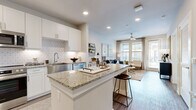 This thoughtfully designed one-bedroom, one-bathroom residence offers a cohesive open-concept floor plan that maximizes every square foot. Wide-plank wood-style flooring flows throughout, tying together each space with a warm, contemporary aesthetic.

The kitchen serves as the heart of the home, showcasing crisp white shaker cabinetry, a geometric patterned tile backsplash, granite countertops, and a full suite of stainless steel appliances including a gas range, microwave, dishwasher, and refrigerator. A central island with granite countertop provides bar seating, making it ideal for casual dining or entertaining.

The kitchen opens seamlessly into the living room, which is bathed in natural light from large windows and a glass-panel door leading to the outdoors. A ceiling fan adds comfort, while neutral wall tones create a calm, inviting atmosphere.

The bedroom is a serene retreat, featuring multiple windows with outdoor views, a ceiling fan, and ample natural light. It connects directly to a well-appointed walk-in closet with multi-tiered shelving and hanging rods.

The bathroom is finished with granite countertops, white cabinetry, an undermount sink, and a tub-shower combination, maintaining the refined aesthetic found throughout the residence.