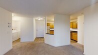 Located in St. Louis Park, MN, this 2-bedroom, 2-bathroom residence offers a practical and comfortable single-floor layout. The open living room features soft carpeting, neutral walls, a textured ceiling, and a sliding glass door that opens to a private balcony with outdoor views — allowing natural light to fill the space. The kitchen is positioned adjacent to the living area and is defined by warm honey-toned cabinetry, dark countertops, a tile floor, a full appliance suite including a stainless steel microwave and range, and a pass-through breakfast bar that connects it to the main living space. The spacious primary bedroom features a bay-style multi-panel window that brings in generous natural light and is finished with plush carpeting. The second bedroom also features carpet flooring and a window with outdoor views. Both bathrooms include a full tub and shower combination with white tile surround and tile flooring. The unit includes two closets with wire shelving systems for ample storage. A dedicated laundry room houses a full-sized Whirlpool washer and dryer. The overall aesthetic is clean and functional, with consistent neutral finishes throughout.