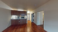 Located on the third floor at 305 E Mill Plain Blvd in Vancouver, Washington, this unit offers a thoughtfully designed single-level layout. Rich, dark hardwood floors extend through the main living areas, creating a warm and polished atmosphere throughout.

The open living area is bright and spacious, featuring a large window that invites natural light and provides views of the surrounding neighborhood. The clean, neutral walls offer a versatile backdrop for a variety of interior styles.

The galley-style kitchen is efficiently designed with dark wood cabinetry, granite-look countertops, and a full suite of stainless and black appliances, including an electric range, built-in microwave, dishwasher, and refrigerator. A peninsula counter separates the kitchen from the living space, ideal for casual dining or additional prep space.

A convenient in-unit stacked washer and dryer is tucked neatly into a dedicated closet just off the main hallway, adding everyday practicality to the home.

The bedroom features plush carpeting, a window with natural light, and a generously sized walk-in closet with a full-width shelf and hanging rod for ample storage. The bathroom includes a soaking tub with a tile surround in warm neutral tones, lending a clean and classic aesthetic. This unit combines functional design with comfortable living in a convenient Vancouver location.