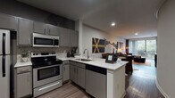 This single-floor residence is thoughtfully designed with a contemporary aesthetic that flows seamlessly from room to room. The kitchen serves as a functional centerpiece, featuring grey cabinetry, a mosaic tile backsplash, white quartz countertops, and a full suite of stainless steel appliances including a range, built-in microwave, dishwasher, and refrigerator. A peninsula counter extends the workspace while opening directly to the living area, creating an ideal layout for entertaining.

The living room is generously proportioned, with wood-style flooring, neutral walls, and large windows that invite natural light and outdoor views. Bold, curated artwork and sculptural wall installations lend an artistic character to the space, complemented by warm-toned area rugs and eclectic furnishings.

The bedrooms offer comfortable retreats, each with wood-style flooring, ceiling fans, and well-sized windows. One bedroom features a striking upholstered headboard wall and high transom windows, while another benefits from a large window with lush outdoor views.

The bathroom is finished with classic white tile, a checkered accent border, a soaking tub with shower, and wood-style flooring, maintaining the cohesive modern design found throughout the residence.