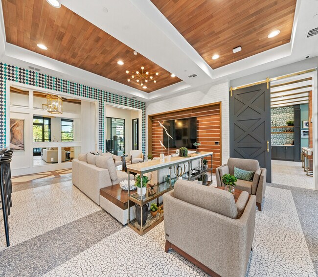 Lujosa sala de estar con una decoración elegante, con lujosos asientos, una elegante lámpara de araña y estanterías abiertas modernas para un ambiente sofisticado. - Elan Crown Point