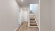 Located at 1219 Fendley Trace in Lawrenceville, GA, this modern three-story home offers four bedrooms and five bathrooms thoughtfully distributed across its floors. The ground level houses an attached garage with concrete flooring, a dedicated utility area with water heater and electrical panel, providing practical functionality from the start.

The main living floor serves as the heart of the home, featuring an open-concept kitchen and living room filled with natural light from multiple windows fitted with blinds. The kitchen is outfitted with crisp white shaker-style cabinetry, light quartz countertops, stainless steel appliances including a range, over-the-range microwave, and refrigerator, complemented by a pantry for added storage. Light hardwood flooring flows seamlessly throughout, enhancing the bright and airy ambiance.

The upper floor hosts the bedrooms, including a generously sized primary bedroom, all featuring the same warm hardwood floors, neutral gray walls, and ample natural light. Bedrooms include closet storage with classic paneled doors. The five bathrooms are clean and modern, each featuring tub-shower combinations with brushed nickel fixtures and white surrounds.

Throughout the home, consistent design choices — neutral tones, recessed lighting, and clean white trim — create a cohesive, move-in-ready atmosphere well suited for comfortable everyday living.