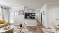Located at 5525 Mansions Bluffs in San Antonio, Texas, this one-bedroom, one-bathroom residence offers a well-designed single-floor layout that maximizes every square foot. Wood-style flooring and crown molding flow consistently throughout, lending a polished, cohesive feel to the entire space.

The open-concept living and dining area welcomes you upon entry, featuring neutral walls, natural light from large windows with blinds, and generous room for comfortable furnishings. The kitchen is a standout, appointed with rich dark-espresso cabinetry, granite-style countertops, black appliances, and a peninsula with pendant lighting overhead — seamlessly connecting to the main living area and providing additional prep and seating space.

The bedroom is a calm, light-filled retreat with windows on multiple walls, crown molding, and direct access to a dedicated walk-in closet fitted with multi-tiered hanging rods and shelving. The full bathroom mirrors the kitchen's design aesthetic with dark cabinetry and matching countertops, creating a consistent style throughout the home. A separate laundry area adds everyday convenience. The overall ambiance is bright, clean, and modern — an efficient yet comfortable residence in the heart of San Antonio.