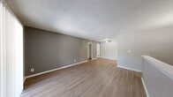 Located at 7984 S Sheridan Rd in Tulsa, Oklahoma, this one-bedroom, one-bathroom unit offers a practical and well-organized layout across a single floor, accessed via a private staircase entry. The open living area is finished with warm wood-look vinyl flooring, neutral gray accent walls, and a textured popcorn ceiling. A ceiling fan provides overhead comfort, while a sliding glass door opens to a private balcony, allowing natural light to fill the space and offering outdoor access. The living area flows toward a compact kitchen outfitted with white cabinetry and a sink, separated by a half-wall partition that adds a subtle architectural detail. The bedroom features plush carpeting, a window with blinds that brings in natural light, and direct access to both a closet and the hallway. A dedicated closet provides additional storage. The bathroom includes a full tub and shower combination with floor-to-ceiling tile surround in warm earth tones, complemented by white cabinetry and wood-look flooring. Clean white trim and baseboards tie the neutral color palette together throughout, creating a cohesive and functional living environment.