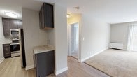This single-floor residence offers a thoughtfully laid-out interior with a clean, neutral aesthetic throughout. The kitchen is well-appointed with dark espresso cabinetry, stone-look countertops, a subway tile backsplash, and a full suite of stainless steel appliances including a refrigerator, range, and over-the-range microwave. Light wood-style flooring runs through the kitchen and entry areas, creating a warm transition into the carpeted living spaces.

The living area is generously proportioned, featuring soft wall-to-wall carpeting, a ceiling fan with light fixture, and a large sliding glass door dressed with vertical blinds that invites natural light and outdoor views. The open sightlines between the living space and kitchen area enhance the overall sense of flow.

The bedroom offers comfortable carpeted flooring, a wide window with horizontal blinds framing outdoor tree views, and a closet with a rod for hanging storage. The bathroom is finished with large-format tile surrounding the tub and shower, a dark-cabinetry vanity with a stone-look countertop, an undermount sink, and a wide wall mirror with overhead lighting. White trim and baseboards throughout unify the space with a crisp, cohesive appearance.