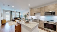 Located at 9302 Fry Rd in Cypress, TX, this thoughtfully designed one-bedroom, one-bathroom residence offers a comfortable and modern living experience across a single floor. The open-concept layout seamlessly connects the kitchen and living room, creating an inviting, functional space ideal for both everyday living and entertaining.

The kitchen is a standout feature, showcasing light wood cabinetry that extends to the ceiling for ample storage, a marble-look granite island with seating, a white subway tile backsplash, and a full suite of stainless steel appliances including a side-by-side refrigerator, range, microwave, and dishwasher. Wood-look flooring flows throughout, adding warmth and continuity.

The living room is bright and welcoming, benefiting from large windows that invite natural light and offer outdoor views. A ceiling fan adds comfort, and the space provides a relaxed yet polished ambiance.

The bedroom is a serene retreat with large windows framing lush greenery, a ceiling fan, and direct access to the bathroom and a well-organized closet with built-in shelving and hanging rods.

The bathroom features wood-look flooring, a dark-toned vanity with a white countertop, and a tiled shower surround, maintaining the home's clean, contemporary aesthetic throughout.