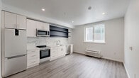 Located at 1201 Vine St in Philadelphia's vibrant Chinatown/Callowhill neighborhood, this thoughtfully designed one-bedroom, one-bathroom unit offers a clean, modern aesthetic throughout its single-floor layout. The open-concept main living area seamlessly combines the kitchen, dining, and living spaces, all finished with light gray wood-look flooring and crisp white walls that maximize the sense of brightness and openness. Recessed lighting illuminates the space, complemented by a window that brings in natural light. The contemporary kitchen features white cabinetry, a marble-look tile backsplash, stainless steel appliances including a range, microwave, and dishwasher, dark open shelving for display, and a full-size refrigerator. The private bedroom is a calm, neutral retreat with the same wood-look flooring and access to a dedicated closet. The hallway connects all rooms efficiently and includes a convenient in-unit laundry area. The bathroom is a standout feature, finished floor-to-ceiling in striking marble-look tile, with a frameless glass walk-in shower, modern vanity with warm wood accents, an illuminated mirror, and polished chrome fixtures. The overall design is cohesive, minimal, and move-in ready.