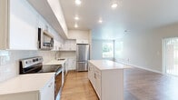 This well-appointed two-bedroom, two-bathroom residence in Loveland, Colorado offers a thoughtfully designed single-floor layout with a clean, modern aesthetic throughout. The open-concept kitchen and living area serves as the heart of the home, where crisp white cabinetry, white quartz countertops, a classic subway tile backsplash, and stainless steel appliances — including a refrigerator, range, and over-the-range microwave — create a functional and stylish space. A kitchen island provides additional prep and gathering space, while light wood-style flooring flows seamlessly into the adjacent living room, which benefits from large windows that invite natural light and offer pleasant outdoor views of surrounding greenery. The hallway connects to both bedrooms and includes a convenient in-unit laundry closet with a full-size washer and dryer. The primary bedroom is a comfortable retreat with wood-style flooring, a window with outdoor views, and access to a private bathroom featuring a white vanity, quartz countertop, and a walk-in closet with built-in shelving. The second bedroom is equally bright and spacious, with its own access to a well-appointed full bathroom complete with a shower-tub combination. Neutral tones and consistent finishes throughout create a cohesive, move-in-ready atmosphere.