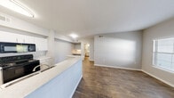 This thoughtfully designed single-floor residence offers a comfortable and functional layout across its 1 bedroom and 1 bathroom. The open-concept living and dining area is anchored by warm wood-look flooring and neutral gray walls, creating a bright and cohesive atmosphere. A kitchen peninsula with a light stone-style countertop and integrated sink separates the kitchen from the main living space, while white cabinetry and black appliances — including a refrigerator, range, and microwave — provide a clean, modern contrast. Natural light filters in through a window fitted with blinds, enhancing the airy feel of the common areas. The bedroom features plush carpeting, a ceiling fan with light fixture, and an arched window that brings in additional natural light and outdoor views. Three closets throughout the unit offer generous storage options. The full bathroom includes a tub-shower combo with white tile surround, wood-look flooring, and white cabinetry. A dedicated in-unit laundry room houses a full-size washer and dryer with overhead shelving for added storage. The space also includes a private balcony and a welcoming entrance, completing this efficiently designed and well-equipped home.