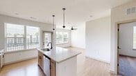 Located at 2220 Berryhill Road in Charlotte, NC, this thoughtfully designed 2-bedroom, 2-bathroom residence offers a modern aesthetic across a single, well-organized floor. The open-concept living, dining, and kitchen area forms the heart of the home, anchored by a large kitchen island with quartz countertops, a matte black faucet, and stylish pendant lighting. Light wood cabinetry, stainless steel appliances — including a refrigerator, range, and over-the-range microwave — white subway tile backsplash, and large windows flooding the space with natural light complete the kitchen. Light hardwood-style flooring flows through the main living areas, while ceiling fans provide comfort throughout. Both bedrooms feature plush carpeting, generous natural light, and ceiling fans. The primary bedroom connects to an en-suite bathroom with a double-sink vanity, quartz countertops, and matte black fixtures. The second bathroom offers a full tub-shower combo with white subway tile and coordinating black hardware. Four closets — including a spacious walk-in — provide ample storage. A dedicated laundry area and utility room add everyday convenience. A private balcony rounds out this well-appointed residence.