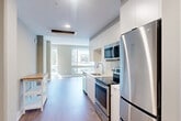 Located at 1772 Church St NW in Washington, DC's vibrant 20036 corridor, this efficiently designed single-floor unit offers a thoughtfully organized layout that maximizes every square foot. Warm hardwood-style flooring flows throughout the space, complementing the neutral taupe and white color palette that lends a clean, contemporary feel.

The kitchen is a standout feature, outfitted with sleek white cabinetry, a classic white subway tile backsplash, and a full suite of stainless steel appliances including a range, built-in microwave, dishwasher, and refrigerator. A single-basin sink sits beneath recessed lighting, and the galley-style configuration ensures an efficient workflow. The kitchen opens naturally into the main living area, which benefits from a large picture window framing views of the surrounding Washington streetscape and filling the room with abundant natural light.

The bathroom is finished to a high standard, showcasing floor-to-ceiling marble-look porcelain tile in the walk-in shower, complete with a frameless sliding glass door and chrome fixtures. Light tile flooring and a modern vanity contribute to the spa-like atmosphere.

Throughout the unit, recessed lighting and clean-lined architectural details reinforce the modern aesthetic, making this a polished and practical urban residence in one of DC's most walkable neighborhoods.