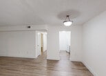 Located at 9000 SW 97th Ave in Miami, FL, this single-floor residence offers a clean, functional layout with a neutral color palette and consistent wood-look flooring throughout. The open living area is generously proportioned, bathed in natural light, and finished with white walls and textured ceilings. A pendant light fixture anchors the main living space, which flows seamlessly toward the entry and the adjacent kitchen.

The galley-style kitchen is well-appointed with dark lower cabinetry contrasted by white upper cabinets and sleek light-colored countertops. White appliances, including an electric range with overhead microwave, refrigerator, and dishwasher, are neatly integrated alongside a stainless steel sink. Track lighting overhead provides functional illumination.

The bedrooms feature ceiling fans with light kits, wood-look flooring, and windows that frame lush, green tropical foliage, offering a serene, private outlook. One bedroom includes dual closets with organized shelving, providing ample storage. The bathroom is finished with white tile flooring, a tub and shower combination enclosed by sliding glass doors, and a vanity with stone-look countertop.

A stacked washer and dryer unit is conveniently accessible within the unit, adding to the overall practicality of this well-maintained Miami residence.