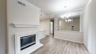 Located at 6225 Love Dr in Irving, TX, this well-appointed 2-bedroom, 2-bathroom single-story home offers a thoughtfully designed layout across a comfortable footprint. The open living and dining area serves as the heart of the home, highlighted by a striking white-mantled fireplace, crown molding, and warm wood-look luxury vinyl flooring that flows throughout the main living spaces. A large wall mirror and stylish multi-light chandelier add a touch of elegance, while windows fitted with blinds allow for ample natural light and outdoor views. The kitchen is both functional and attractive, featuring crisp white cabinetry, light quartz countertops, a skylight, and stainless steel appliances including a refrigerator, range, and microwave. The spacious primary bedroom offers generous proportions, plush carpeting, and a ceiling fan. The second bedroom is equally comfortable, with carpeted floors and a window that brings in natural light. Both bathrooms are clean and classic, with the full bath featuring a tiled tub-shower surround. A dedicated laundry room with side-by-side washer and dryer adds everyday convenience. The overall ambiance is bright, neutral, and move-in ready.
