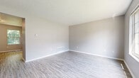 Located at 176 Eagle Creek Dr in Erlanger, Kentucky, this three-bedroom, two-bathroom home is thoughtfully laid out across three floors. The main level features a bright living room with light gray walls, wood-look vinyl plank flooring, and a large front-facing window that draws in abundant natural light. The kitchen is well-equipped with white shaker-style cabinetry, granite-look countertops, a stainless steel dishwasher, and a window above the sink overlooking lush greenery outside. Both bathrooms offer clean, functional designs with white tub-shower combinations, white vanities, and wood-look flooring. The bedrooms feature neutral gray walls and plush carpeting, with several rooms receiving natural light through gridded windows. A dedicated hallway and staircase connect the floors efficiently. The basement level provides generous unfinished space with a painted concrete floor, exposed wooden joists overhead, a window for natural light, and an electrical panel — offering strong potential for storage or future finishing. The exterior is surrounded by mature trees, lending a sense of privacy and greenery to the property.