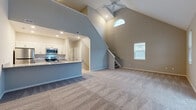 This two-story home in Green, Ohio, is thoughtfully designed across two equally sized floors, offering a well-balanced layout for comfortable living. The main floor centers on an open-concept living room and kitchen, immediately distinguished by soaring vaulted ceilings and a ceiling fan that enhance the sense of volume and airflow. A arched upper window floods the living area with natural light, while carpet flooring adds warmth underfoot. The kitchen features white shaker cabinetry, granite countertops, stainless steel appliances including a range, microwave, dishwasher, and refrigerator, and wood-look luxury vinyl plank flooring. A sliding glass door in one of the rooms provides direct outdoor access and additional natural light.

Upstairs, the generously sized primary bedroom offers vaulted ceilings, a dedicated closet with wire shelving systems, and a calm, neutral palette. Additional bedrooms include carpeted floors and angled ceilings, each with its own character. The three bathrooms are finished with granite-topped white vanities, wood-look tile flooring, and clean, modern fixtures. Carpeted staircases with white railings connect both levels seamlessly, completing this well-appointed home.