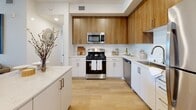 This thoughtfully designed single-floor residence in Modesto, California offers a clean, contemporary aesthetic carried consistently throughout every room. The kitchen is a standout space, showcasing a two-tone cabinetry design that pairs warm wood upper cabinets with crisp white lower cabinets, complemented by light quartz countertops, a subway tile backsplash, and a full suite of stainless steel appliances including a gas range, built-in microwave, dishwasher, and refrigerator. Light hardwood-style flooring flows seamlessly from the kitchen into the dining and living areas, where a dedicated dining nook provides an intimate setting for meals. The bedrooms are bright and inviting, each featuring large windows that draw in natural light and offer views of the surrounding neighborhood. The primary bathroom is generously sized with a wide vanity, white cabinetry, and ample counter space, while a second full bathroom mirrors the same clean, modern design. Throughout the residence, the white walls and light flooring create a cohesive, airy atmosphere. The overall layout, as seen in the dollhouse view, is efficiently organized, offering comfortable living spaces with a polished, move-in-ready finish.