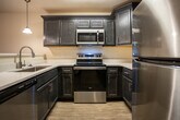 Located at 2749 River Rock Dr in Morristown, Tennessee, this single-floor residence offers a well-designed layout with a practical and comfortable living environment. The kitchen is a standout feature, showcasing rich dark cabinetry, white countertops, and a full suite of stainless steel appliances including a refrigerator, electric range, and built-in microwave. A breakfast bar with pendant lighting connects the kitchen to the adjacent living area, creating an open and functional flow. Light wood-look flooring runs through the kitchen and entry areas, while plush carpeting extends throughout the living spaces and bedrooms, adding warmth underfoot. Multiple rooms are equipped with ceiling fans with integrated lighting, promoting air circulation and comfort. Bedrooms are generously sized, with at least one featuring a walk-in closet and direct access to a bathroom. Natural light enters through windows fitted with blinds, offering views of the surrounding neighborhood. A bathroom includes a dark wood vanity with a white countertop sink and an oval mirror with contemporary lighting above. A rear door leads to an outdoor area, providing convenient exterior access. The overall interior palette features neutral, light tones throughout, creating a clean and move-in-ready atmosphere.