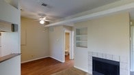 This single-floor residence offers a practical and comfortable layout designed for easy living. The main living area serves as the heart of the home, showcasing warm hardwood flooring that adds character and richness to the space. A tile-surround fireplace anchors one wall, providing a classic focal point and a cozy atmosphere. Built-in shelving adjacent to the fireplace offers convenient display and storage options, adding both functionality and architectural interest to the room. A ceiling fan with integrated lighting is centrally mounted, ensuring comfortable airflow throughout the space year-round. Exposed structural beams add a subtle design element to the ceiling, contributing to the room's character. The neutral, warm-toned walls create a versatile backdrop that complements a variety of furnishing styles. A bathroom is conveniently accessible directly from the living area, featuring essential fixtures. The overall ambiance of the space is understated and practical, with clean lines and a straightforward layout that provides a solid foundation for personalization and comfortable everyday living.
