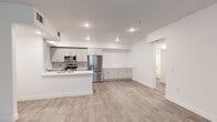 This well-designed 2-bedroom, 2-bathroom single-floor residence offers a clean, modern aesthetic with consistent finishes throughout. The open-concept layout connects the kitchen and living area seamlessly, creating a bright and functional shared space. The kitchen is a standout feature, equipped with gray shaker-style cabinetry, a quartz waterfall island with an undermount sink and a sleek pull-down faucet, subway tile backsplash, and a full suite of stainless steel appliances including a gas range, microwave, and French door refrigerator. Additional lower cabinetry with quartz countertops extends along an adjacent wall, offering generous storage and prep space. The living room is open and airy, featuring light wood-look flooring, recessed lighting, and roller shade windows that allow natural light to filter in. Both bedrooms continue the wood-look flooring and include ceiling fans and roller shade windows. The primary bedroom is spacious and well-proportioned. Each bathroom features gray shaker vanities with white quartz countertops, undermount sinks, large framed mirrors, and a tub-shower combination with subway tile surround. Wood-look tile flooring ties the bathrooms cohesively to the rest of the unit. A hallway connects the main living areas to the bedrooms and bathrooms, contributing to an efficient and logical floor plan.