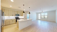This well-appointed 2-bedroom, 2-bathroom residence in Roanoke, TX offers a thoughtfully designed single-floor layout with a clean, modern aesthetic throughout. The open-concept kitchen and living area serves as the heart of the home, showcasing light wood cabinetry with matte black hardware, white quartz countertops, stainless steel appliances, and a central island with pendant lighting overhead. Light wood-tone flooring runs through the main living areas, contributing to the bright, airy atmosphere. The spacious living room receives generous natural light through large windows and a glass door that opens to a private balcony, complete with a ceiling fan for year-round comfort. The primary bedroom is generously sized, featuring direct access to a full bathroom equipped with a soaking tub, tiled shower surround, and a walk-in closet with built-in shelving. The second bedroom is finished with plush carpeting, a ceiling fan, and a large window with outdoor views. Four closets throughout the unit provide ample storage. A dedicated laundry area adds everyday convenience. The overall design palette of neutral tones, natural wood accents, and crisp white finishes creates a cohesive, contemporary living environment.
